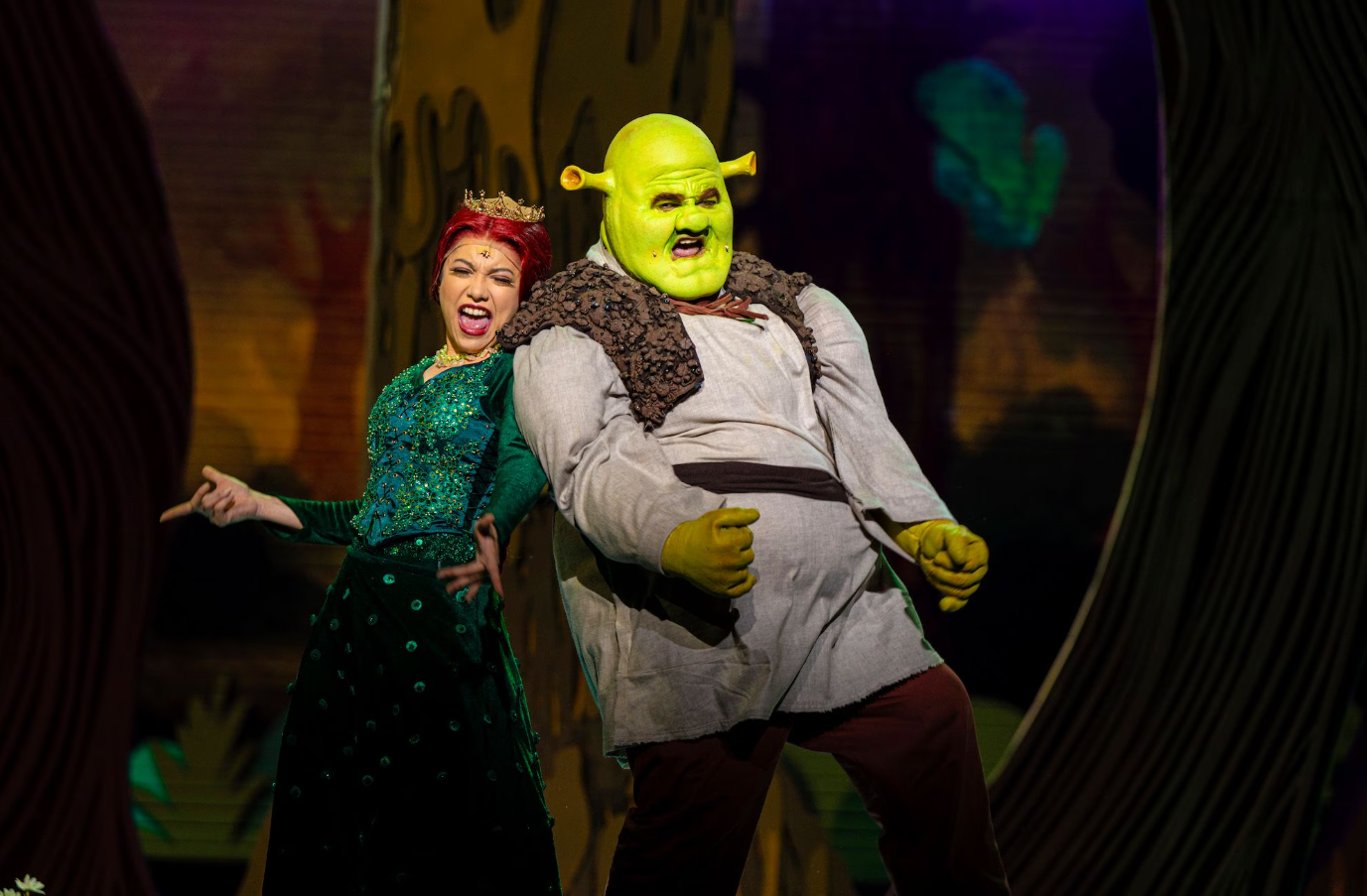 Performers in full ogre and princess character makeup and prosthetics on stage.
